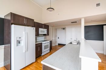 A renovated kitchen with white appliances and dark wood cabinets